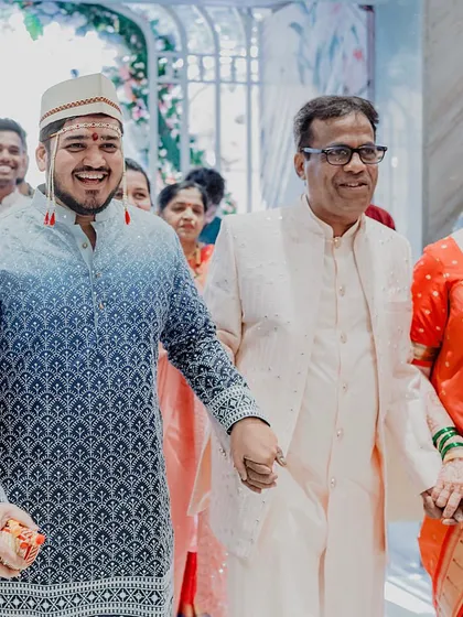 The groom's proud entrance, holding hands with his parents. We believe in capturing the family bonds that are at the heart of every wedding.