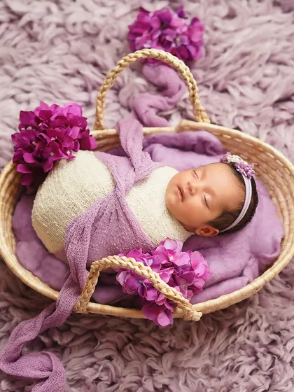 Another angle of the purple floral theme, showing the baby nestled in a wicker basket. The textures of the wrap, flowers, and basket complement each other perfectly.