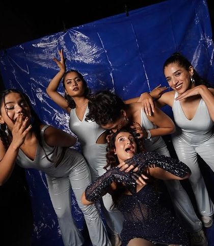 A fun, playful pose with the artist and dancers against a blue backdrop during a photoshoot for a show. Our team chemistry shines through both on and off the stage.