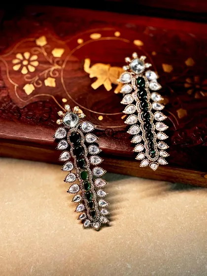 Modern elegance with a touch of tradition. These long, sleek earrings feature leaf-like motifs in polki and deep green stones, perfect for a cocktail party.