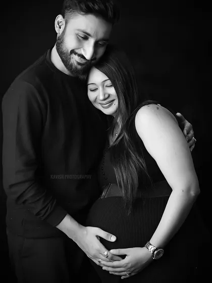 A warm embrace captured in a black and white studio maternity shoot, focusing on the couple's connection.