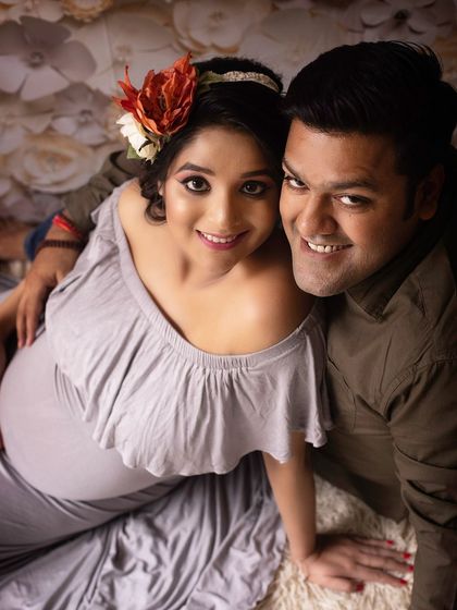A happy, high-angle shot of an expecting couple against a floral backdrop. This pose feels intimate and joyful, drawing the viewer into their happy moment.