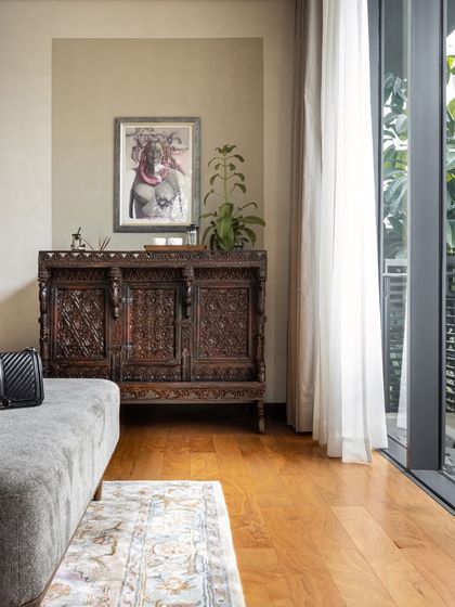 An antique carved console, sourced from a market in Kochi, sits beside a large window, adding a layer of history and character to this bedroom.