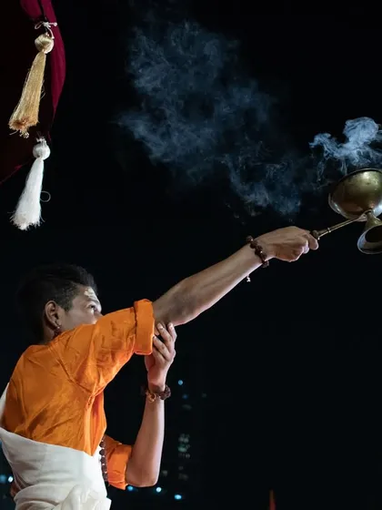 A priest performing a ritual with incense during the Dev Deepawali aarti, the smoke curling into the night air, adding to the mystical atmosphere.