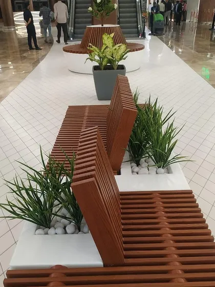 For this wide corridor at Lulu Hypermarket, I designed these modern slatted wood benches with built-in planters. This solution adds comfortable seating and greenery without cluttering the walkway, using artificial grasses for a clean, no-maintenance look.