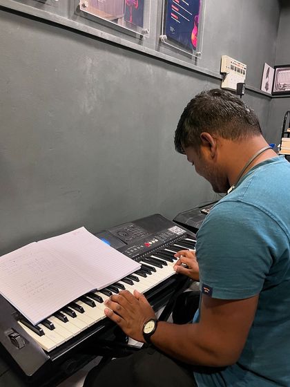 An adult student practices from sheet music during his keyboard lesson. We emphasize learning to read music to build versatile and independent musicians.