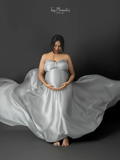 A duplicate of image 17, this shot emphasizes the beautiful way the silver gown spreads out, cradling the mother and her bump in elegance.