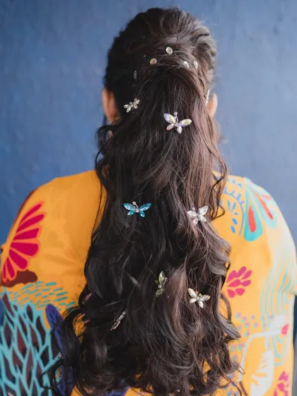 A close-up of the whimsical hairstyle, featuring butterfly beads scattered through her ponytail. It's these little details that make a look unique and personal.