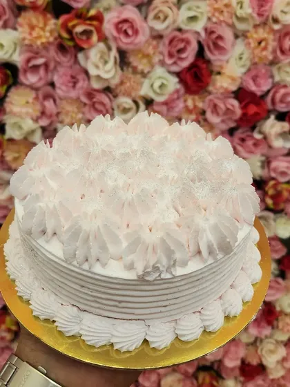 A whimsical and fun Cotton Candy cake. The light pink frosting and fluffy piped topping evoke the sweet, airy taste of cotton candy, making it a perfect choice for kids' parties or for the young at heart.