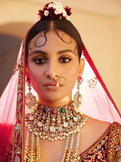 A striking close-up of a bride styled for the "Roopkatha" campaign. The focus is on the magnificent Navratna-style choker and the delicate, artistic swirls of her hair, creating a portrait of classic, regal beauty.