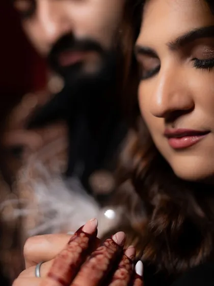 A beautiful, soft-focus shot of the bride's hand on her groom's, with her henna-stained fingers. It’s a small detail that speaks of intimacy and connection amidst the glamour of the cocktail night.