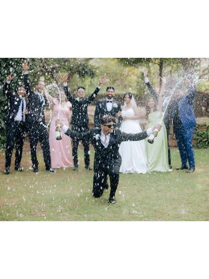 An explosion of joy and champagne as the groomsmen celebrate with the happy couple.