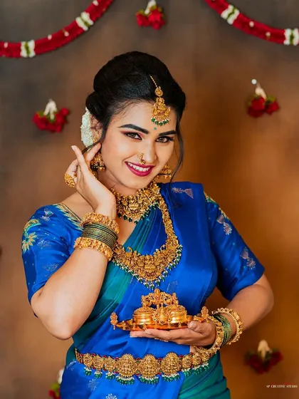 This image is a perfect example of our product-in-context photography. The model, dressed in a beautiful blue silk saree, presents a small, ornate gold item, making it an ideal shot for a jewelry or luxury goods brand catalogue.
