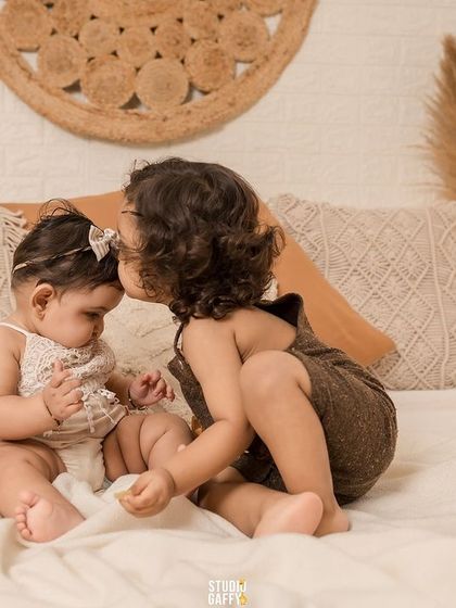 A sweet kiss on the forehead between two young siblings, a truly heartwarming moment.