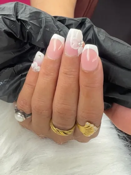 A classic French ombre look elevated with delicate 3D flowers and pearl accents. This is a perfect example of elegant and detailed nail art.