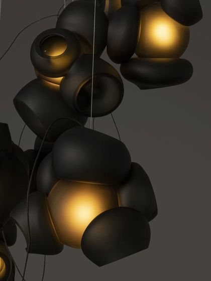 A cluster of dark grey Bocci 100 pendants, their warm light creating a moody and intimate atmosphere.