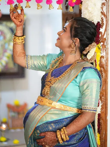 This radiant client is embracing her motherhood journey with timeless elegance in our blue and aqua Kanchipuram silk saree for her baby shower.