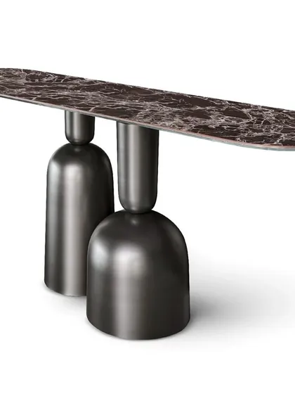 A studio shot of the console table with a dark, richly veined marble top, showcasing its sculptural and innovative design.