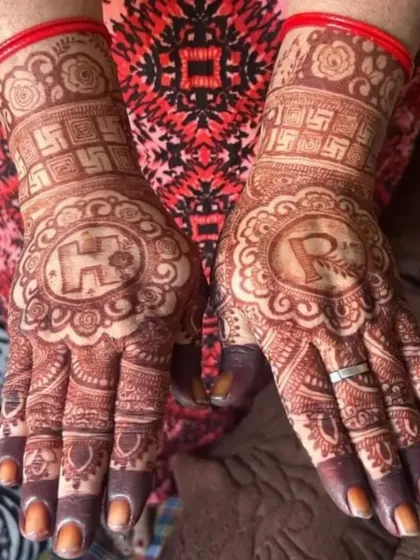 The beautiful result of natural henna. This client's hands show a rich, dark stain with personalized initials 'H' and 'R' in the center.