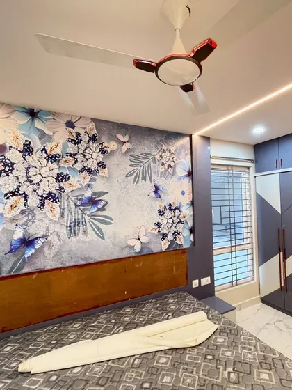 A finished bedroom project featuring a custom floral wallpaper behind the headboard. The cool blue and white tones of the wallpaper complement the room's grey wardrobe and modern interior design.