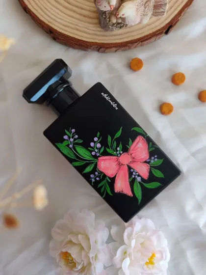 This perfume bottle is adorned with a hand painted pink bow and delicate botanicals. The ribbon design adds a graceful flow and a touch of classic charm, making it a truly unique and beautiful piece.