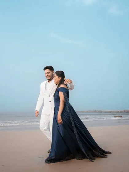 A romantic walk on the beach. This shot showcases the elegant silhouette of the navy blue gown, which can be worn with or without its dramatic trail for different looks.