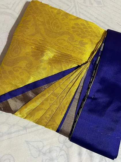 A yellow silk saree with a royal blue border, folded neatly to keep it ready to wear.