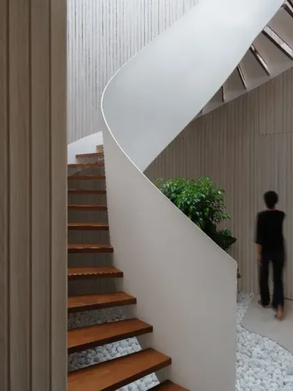 I believe staircases can be sculptural centerpieces. This helical staircase in a contemporary penthouse creates a striking visual impact with its dynamic, swirling form contrasted against the clean, linear aesthetic of the fluted wood wall.