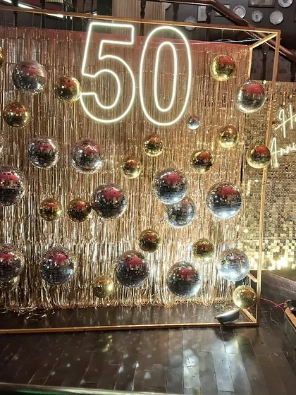 Another perspective of the grand 50th-anniversary installation. The structured frame adds a modern architectural element to the free-flowing glitter of the fringe and disco balls.