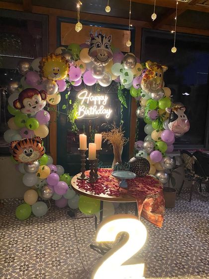 A jungle animal themed second birthday party with a circular balloon arch and large marquee number '2'.
