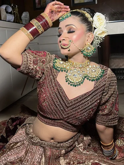 A close-up on the heavy emerald and polki jewellery paired with our wine-colored lehenga. This highlights the quality and detail of our rental jewellery.