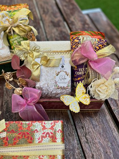 A stunning wedding hamper featuring a rich, traditional color palette of red, green, and gold. The intricate wrapping paper and butterfly embellishments add a touch of whimsical elegance.