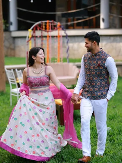 A happy couple at their vibrant Mehendi ceremony in Coorg. The bride's colorful lehenga perfectly complements the festive, floral decor.