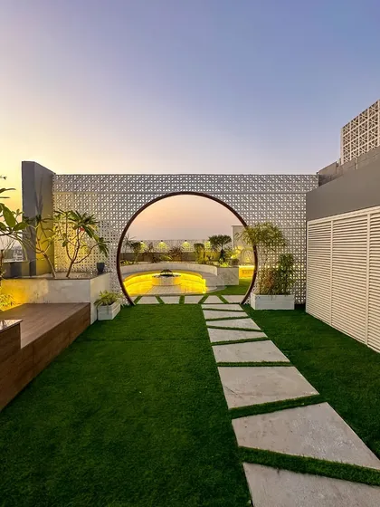 We love making a grand entrance. This custom moon gate, set against a modern jaali wall, creates a stunning entryway to a hidden garden, perfectly framing the sunset view. It’s a statement piece that adds architectural drama and a sense of discovery.