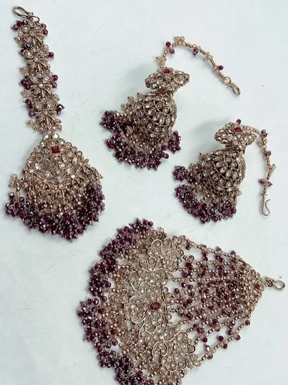 This deep wine-colored beaded set is a unique choice for your Mehendi function. The rental set includes a maang tikka, hathphool, and matching earrings.