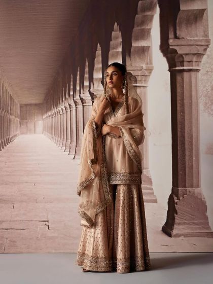 A full-length view of a beautifully detailed sharara suit. The soft color palette and traditional silhouette are styled to create a look of timeless elegance for any wedding event.