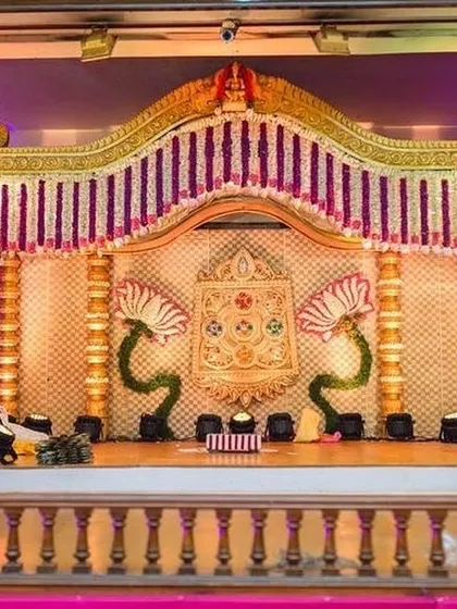 A wedding mantapa featuring unique lotus-shaped floral motifs and a backdrop of delicate flower strings. The design combines traditional elements with artistic floral work for a distinctive look.