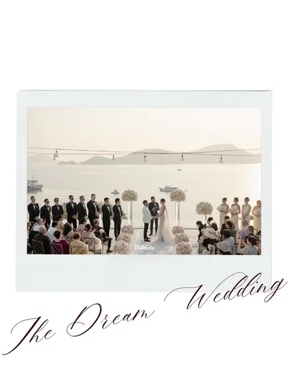 A wide shot of the stunning white wedding setup, overlooking the ocean. It captures the scale and beauty of their dream wedding.