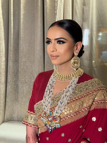 A profile shot that emphasizes the dramatic winged eyeliner and the beautifully crafted low bun. This angle showcases the clean lines and elegance of the complete look.