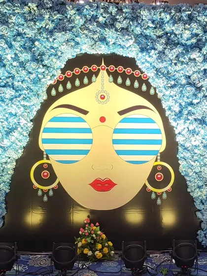 I love adding a touch of fun and personality to your events. This quirky, custom-designed photo booth, featuring a cool bride illustration against a wall of blue flowers, becomes a favorite spot for guests at a Haldi function.