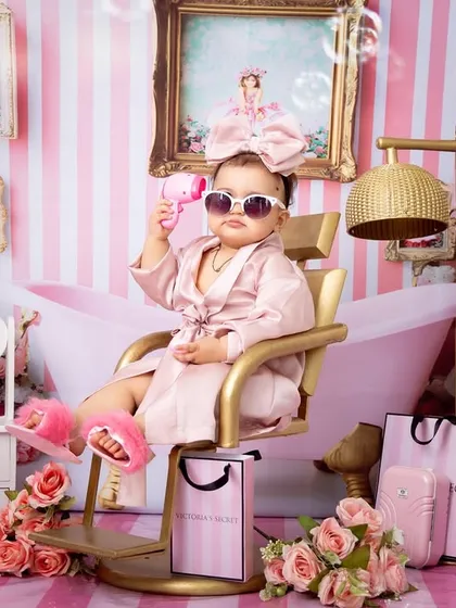 This baby girl strikes a pose with sunglasses and a bubble gun in her pink spa-themed photoshoot. The image is full of attitude and charm, demonstrating a playful and highly stylized session.