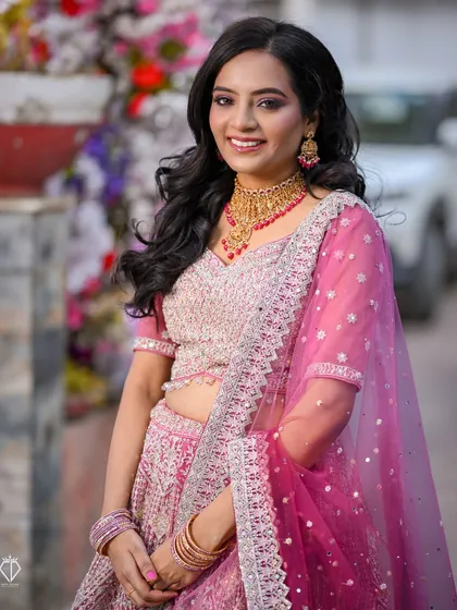 A beautiful outdoor portrait of the bride-to-be at her engagement ceremony, her pink lehenga vibrant against the natural surroundings.