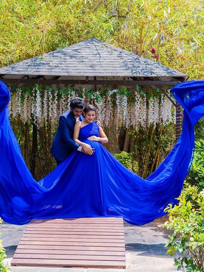 A stunning maternity shot with a flowing blue gown at the garden gazebo.