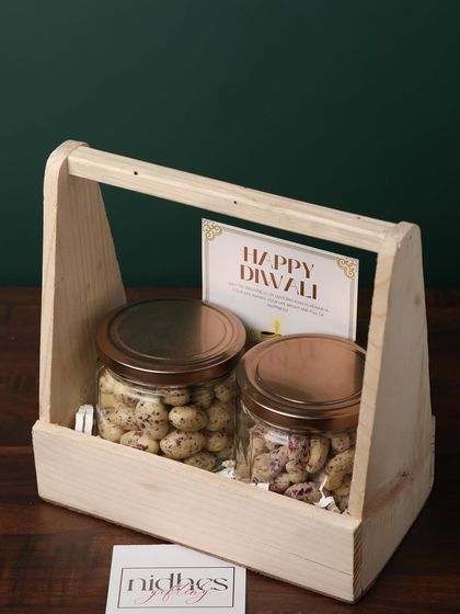A clean and simple gift, this wooden basket holds two glass jars filled with premium coated nuts, accompanied by a Diwali card. It's an elegant and healthy gifting option.