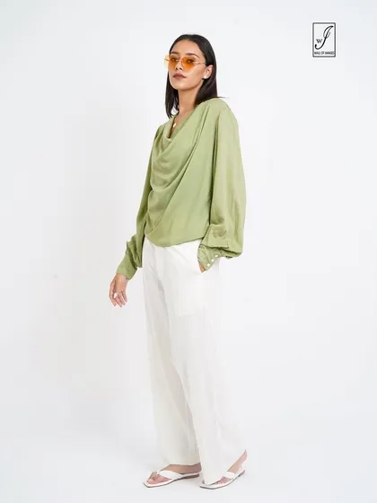 A chic look featuring a cowl-neck green top and white pants, perfect for a sophisticated fashion brand's catalogue.