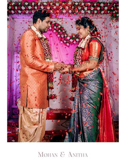 The moment of the ring exchange, with flower petals showering the happy couple. A perfect capture of a joyous celebration.