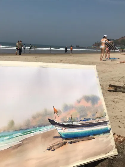 The completed watercolour painting of a boat on the Goan beach, with the sea and people in the background.