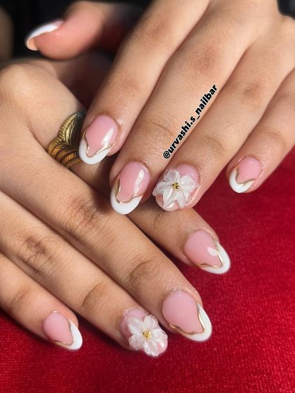 I love adding a touch of luxury to a classic French manicure. Here, I outlined the white tips with a fine gold line and added small 3D flowers for a look that's perfect for an engagement or pre-wedding shoot.
