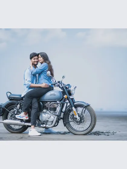 A cool and casual pre-wedding photo of a couple on a Royal Enfield motorcycle at Kelva Beach. This captures a fun, adventurous vibe for couples who want their photos to feel relaxed and authentic.