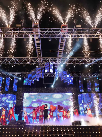 The entire stage comes alive with pyrotechnics during a dance performance, highlighting the dynamic and high-energy production value of the Sangeet.